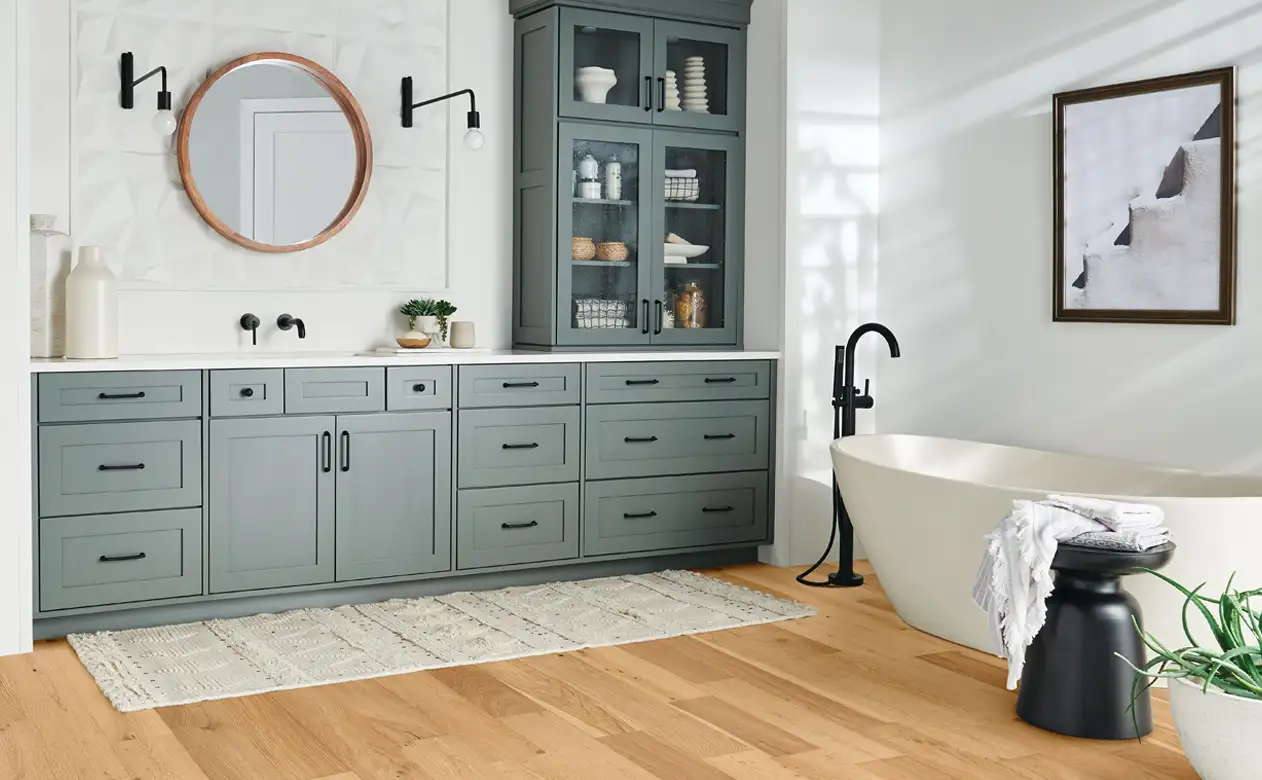 light hardwood waterproof floors in bathroom with gray cabinets and soaker tub